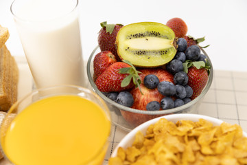 Healthy breakfast. bread, orange juice, strawberry, blueberries, kiwi, milk and cereal in bowl on mat background. Healthy food