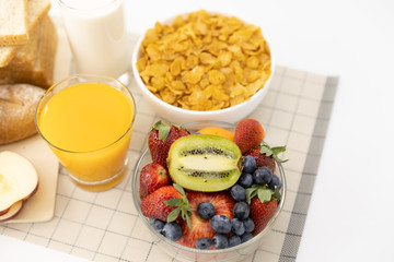 Healthy breakfast. bread, orange juice, strawberry, blueberries, kiwi, milk and cereal in bowl on mat background. Healthy food