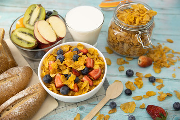 Healthy breakfast. bread, fruit, strawberry, blueberries, kiwi, milk in glass and cereal in bowl on mat and wooden table. Background Healthy food.