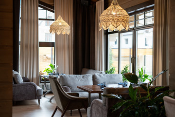 Part of luxurious restaurant with wooden tables and comfortable sofas
