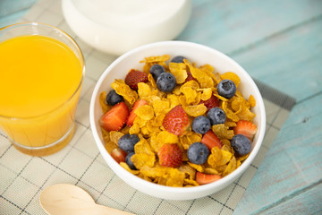 Healthy breakfast. orange juice, fruit, strawberry, blueberries and cereal in bowl on mat and wooden table. Background Healthy food.