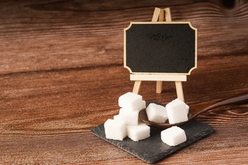 Sugar cubes with wooden spoon. Unhealthy eating concept