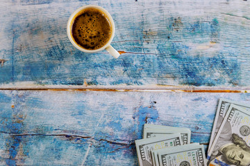 Hundred dollar bills with white cup of espresso coffee