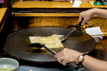 Thai woman cooking and selling traditional Thai sweet pancakes Roti on the street of Khao Lak in Thailand.