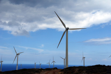 Fototapeta premium wind power plants on a mountain against a background of blue sky and sea