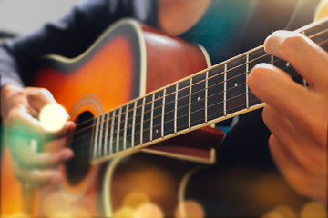 Obraz na płótnie Canvas Man's hand playing acoustic guitar, close up. Bokeh