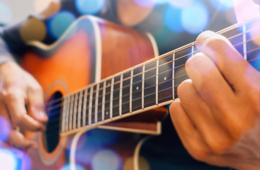 Man's hand playing acoustic guitar, close up. Bokeh