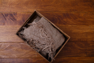 An old brown wooden box with old burlap on dark wooden background.  Shabby chic or rustic style