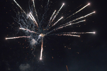 A few volleys of festive fireworks in the night sky, red-yellow.