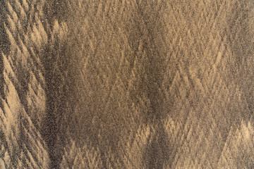 Interesting textured patterns formed in the low tide zone of fine sand in two colors: ordinary golden and black lava