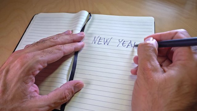 hand writing new year's resolutions in a notebook. New year wishes or goals concept