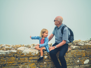 Toddler and grandfather sitting on a wall in the mist