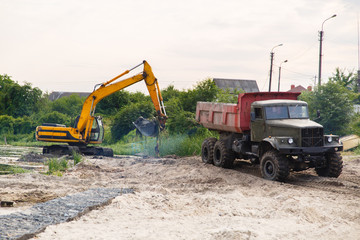 excavator is working on the site. Strengthening the coastline with a stone. Sand and gravel. Construction works with bulldozer. Selective focus