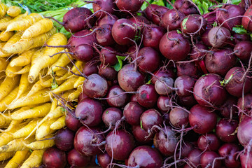A pile of red Onions, and yellow carrots at a farmers market in Union Square New York City.