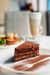 chocolate dessert on a white plate on a light table in a restaurant. Close-up. Traditional chocolate cake