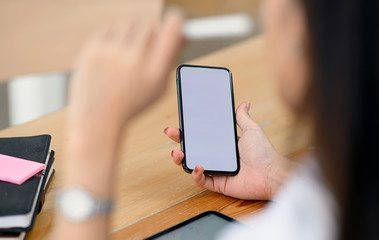 Closeup female hand holding smartphone with blank screen for graphics display montage.