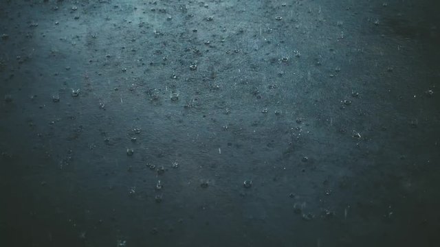 Heavy rain falling on asphalt, dark weather, close up slow motion
