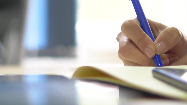 Closeup to a female hand writing in a notebook 