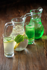 Different soft drinks in transparent jugs on a dark wooden background. menu for catering