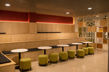 Row of soft velvet chairs by white small round tables inside modern cafe