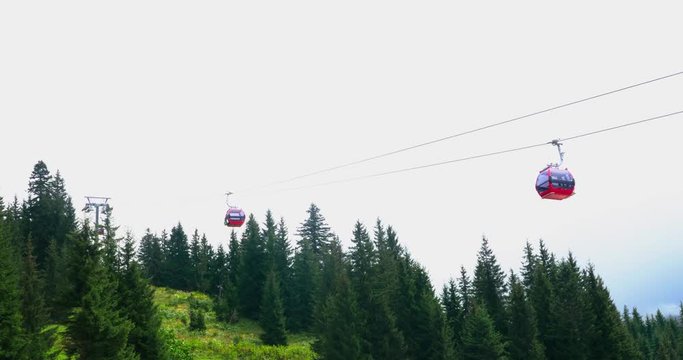 Cable lift (ropeway) movement, landscape view above hills and forest, real time