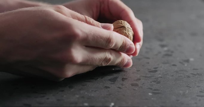 Slow motion closeup man hands opens walnut