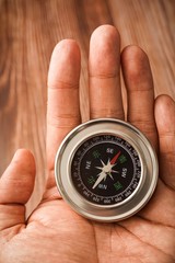 Metallic compass on wooden background