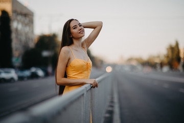 A young woman stands on a background of cityscape.