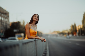 A young woman stands on a background of cityscape.