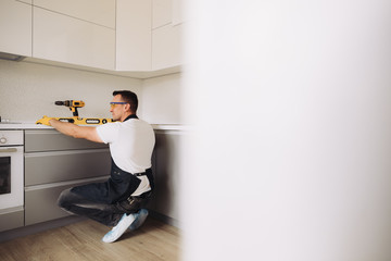 Maintenance man installing kitchen furniture