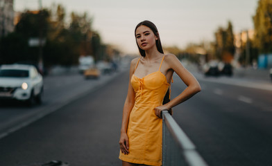 A young woman stands on a background of cityscape.