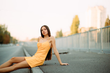 A woman sits on sidewalk on a background of cityscape.