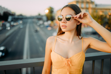 Woman stands on the bridge above the road on a background of cityscape.