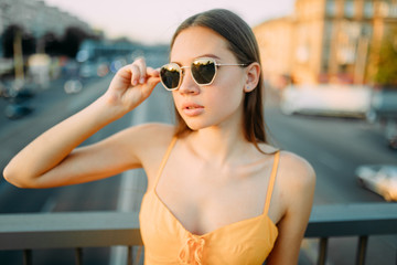 Portrait of woman on the bridge above the road on a background of cityscape.