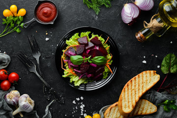 Beet salad with onions in a black plate on a black background. Top view. Free space for your text.
