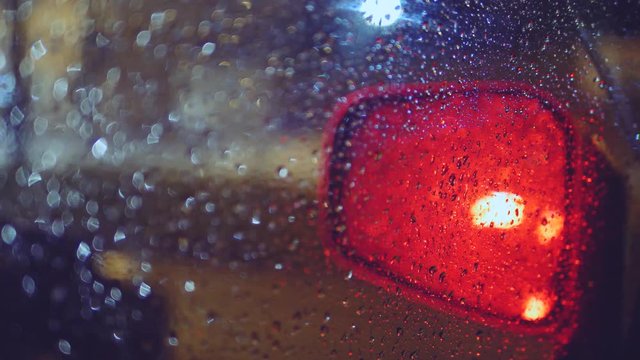 Rain dropping on a car window, side view mirror, red light wipers on, 4K