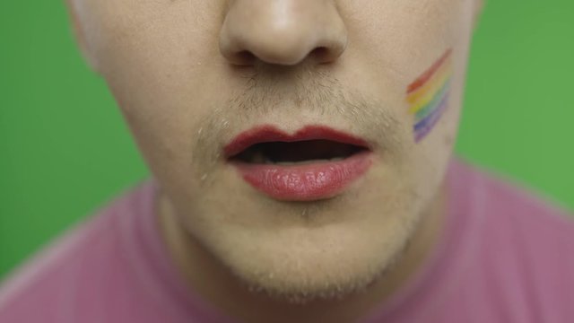 Bearded man with painted lips licks them sexually. LGBT community. Transsexual
