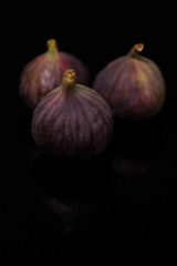 Ripe figs with reflection on black glass