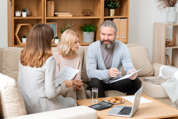 Bearded man looking through paper while consulting with real estate agent