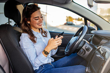 Woman driver using a smart phone in car. Woman driver using a smart phone in car. Leisure, road trip, technology, travel and people concept - Happy woman driving car with smarhphone