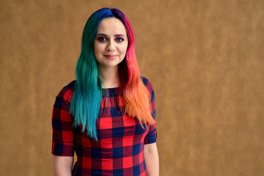 Portrait of a pretty girl with multi-colored hair and make-up on a beige background. Stands with a smile in various poses in the studio.
