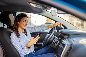 Fototapeta na wymiar Portrait of a young woman texting on her smartphone while driving a car. Business woman sitting in car and using her smartphone. Mockup image with female driver and phone screen