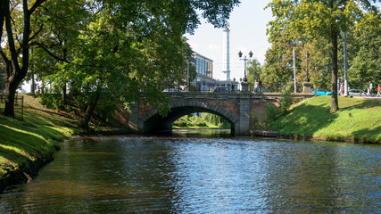 Small canal, river stone bridge in city park