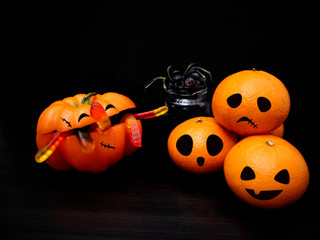  Halloween decoration idea with fruits. Creative and funny mandarins and bell pepper with Jack o lantern faces on dark background.