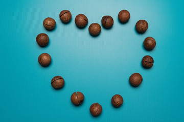 Fototapeta na wymiar Macadamia nuts heart studio image. Macadamia logo heart on Holiday. Heart made of nuts on a blue background.