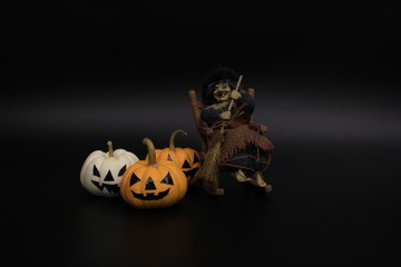 Decorated pumpkin lanterns and old witch who hold a broom stick and sits on rocking chair in Halloween concept.