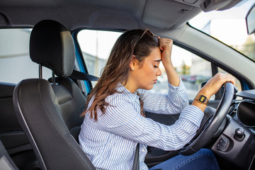 Business woman having headache taking off her glasses has to make a stop after driving car in...