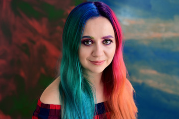Close-up portrait of a pretty girl with multi-colored hair and make-up on a colored background. Stands with a smile in various poses in the studio.