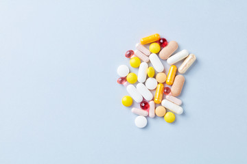 Multicolor vitamins and supplements on bright paper background. Top view. Copy space. 