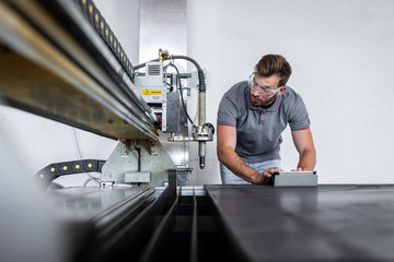 Young engineer setup plasma cutter for work in metalwork workshop.